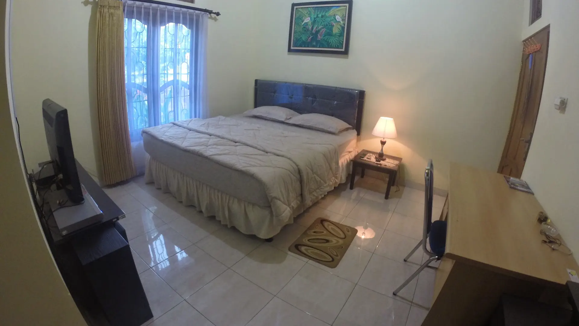 Guest bedroom with a bed, television and painting