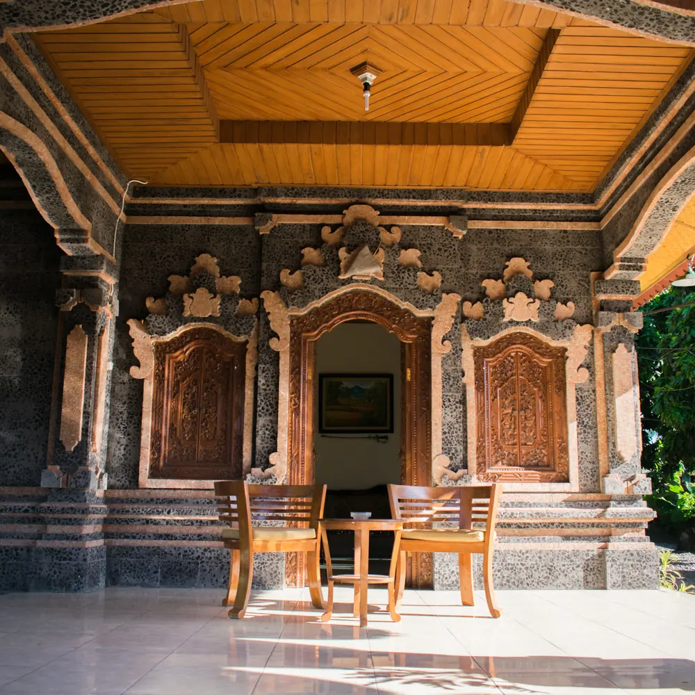Guest room terrace with carved stone, wooden doors and two chairs