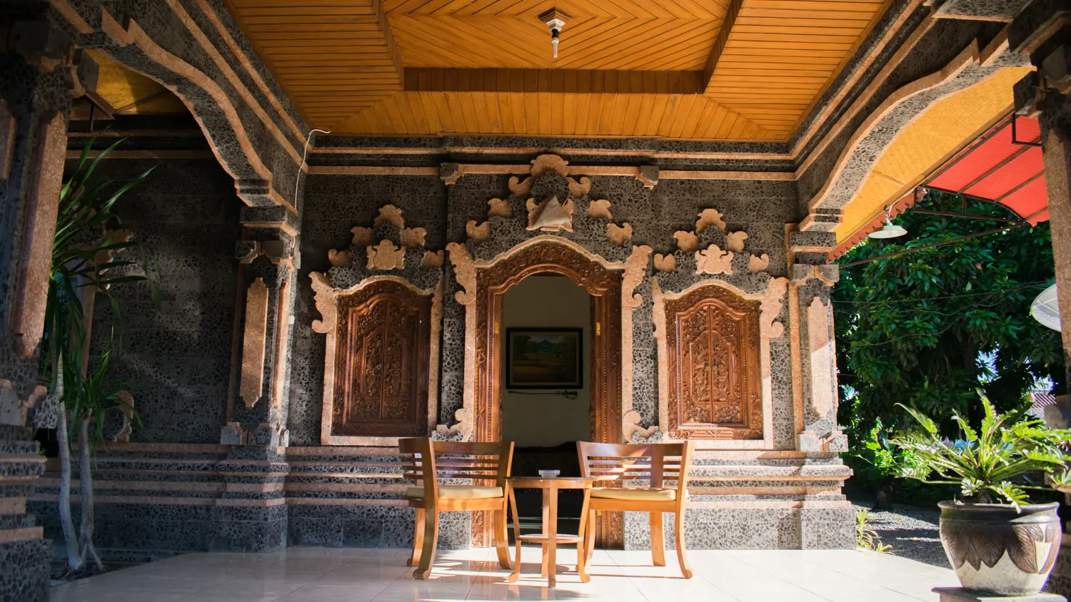 Guest room terrace with carved stone, wooden doors and two chairs