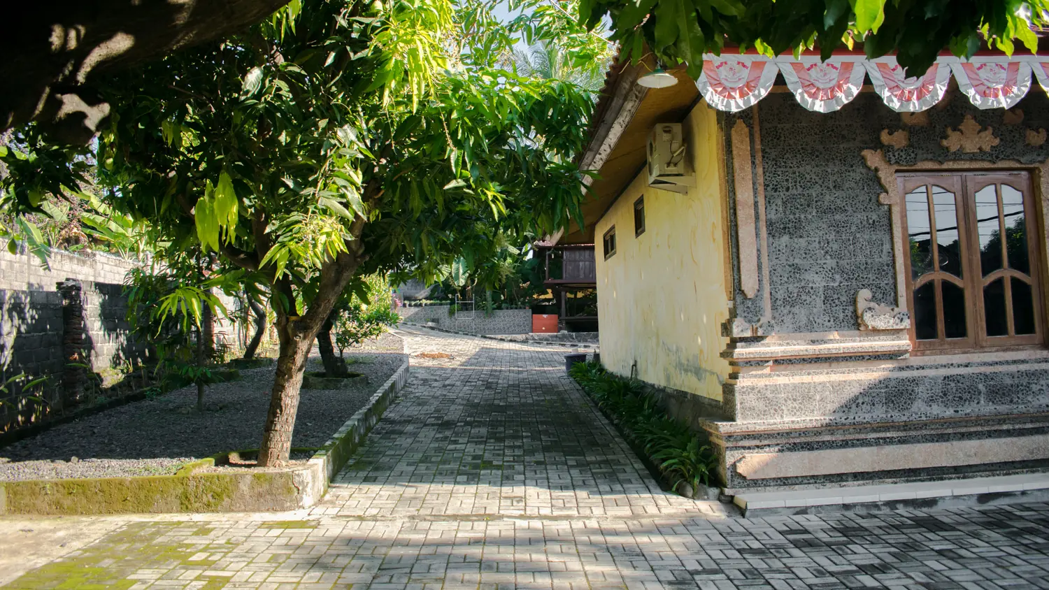 Paved path past the guest rooms under shady trees