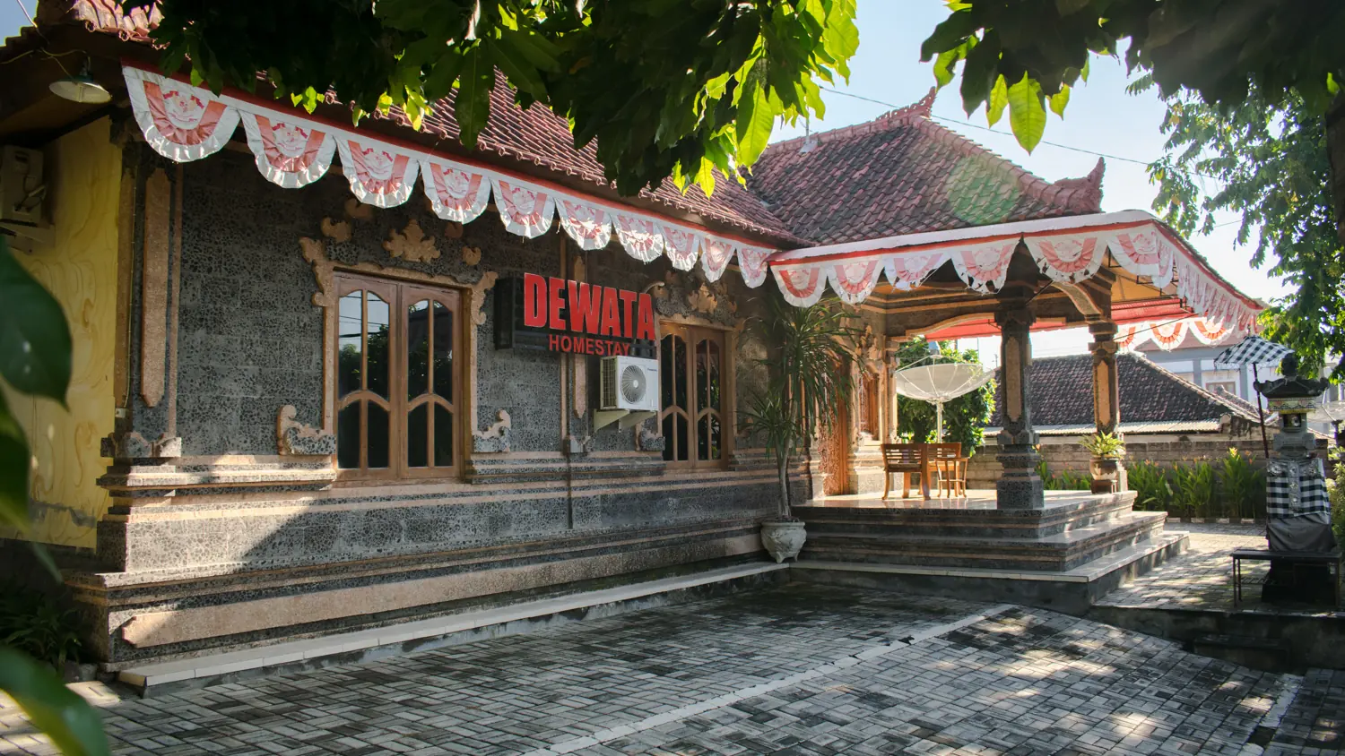 Guest building with the Dewata Homestay sign and fringe along the roof