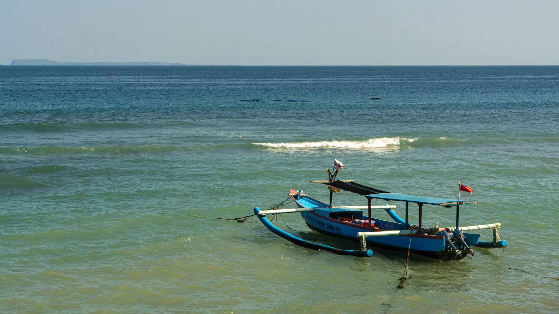 A jukung, a Balinese outrigger boat, on calm blue water