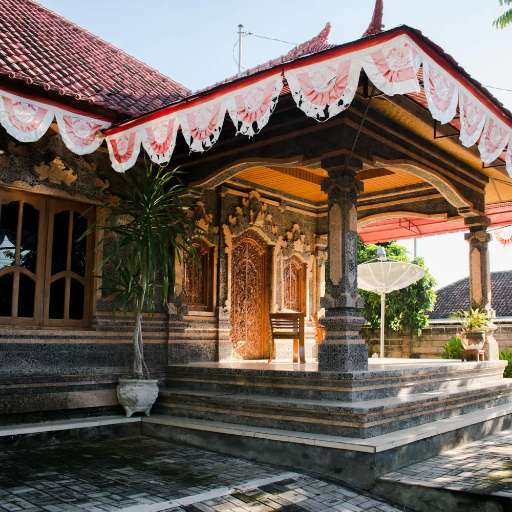 Carved Balinese pavilion with red and white ider-ider fringe along the eaves