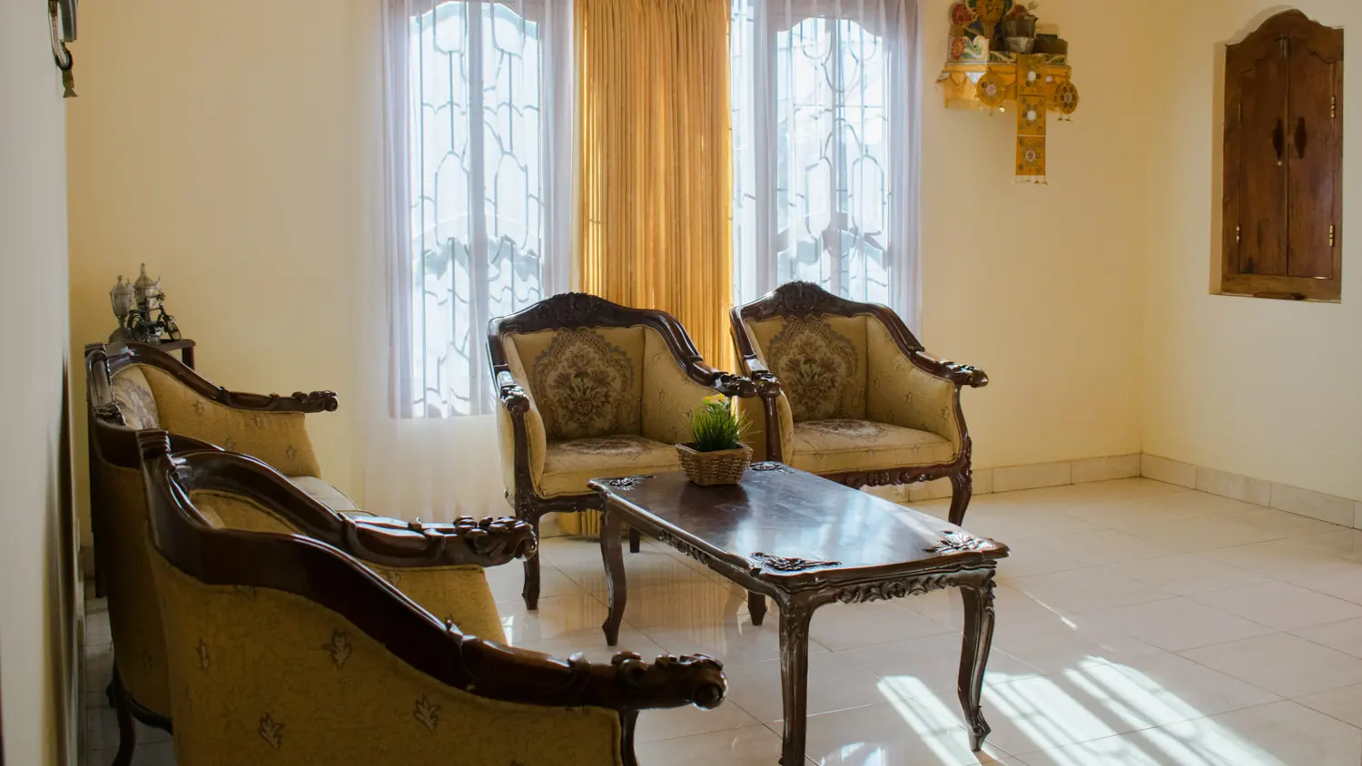 Sitting room with carved wooden armchairs and a glass table